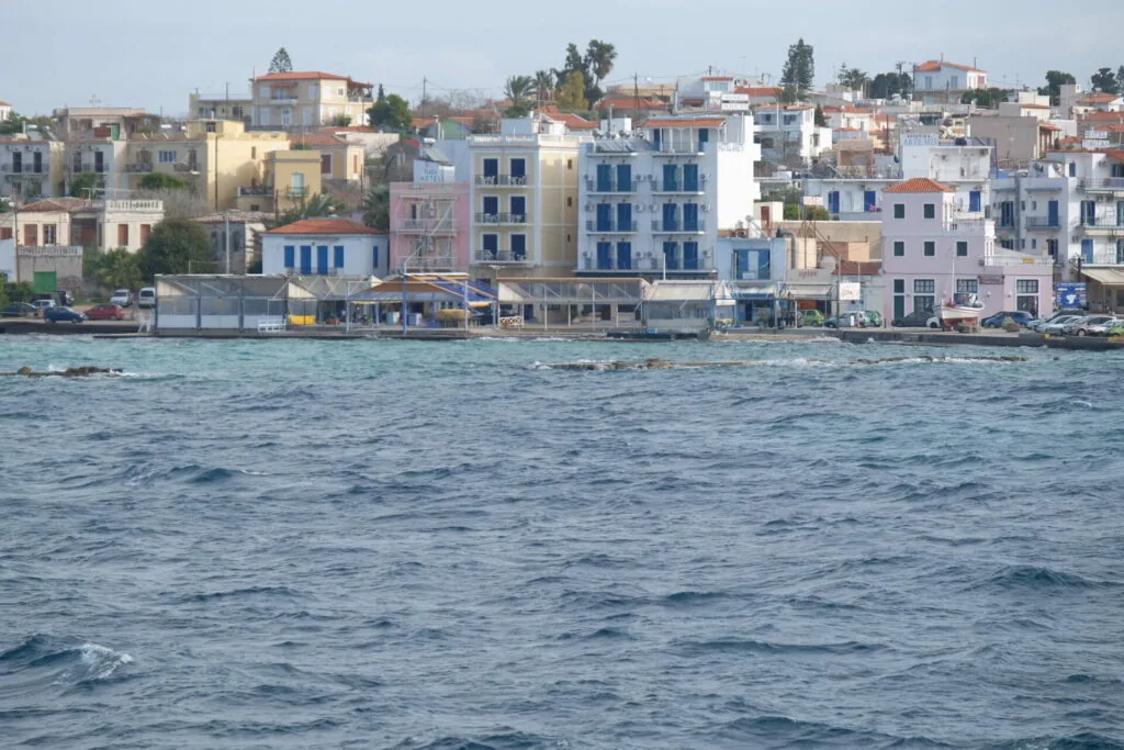 Colorful waterfront buildings along Mediterranean shoreline with blue shutters and fishing boats