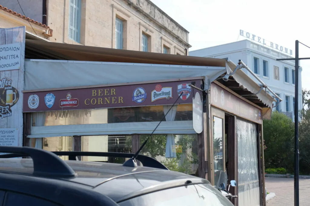 Beer Corner storefront with brown signage and retractable awning, situated on street corner below residential buildings