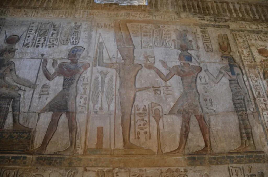 Ancient Egyptian wall relief depicting figures in traditional dress with hieroglyphic inscriptions and cartouches