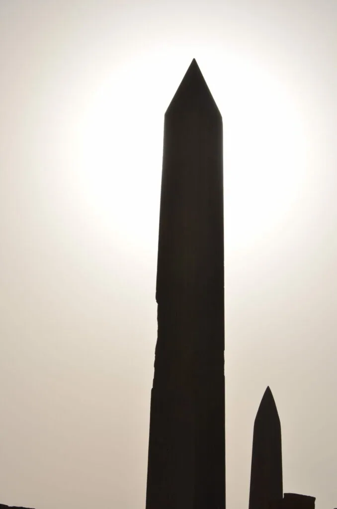 Silhouette of tall obelisk with pointed top against light sky