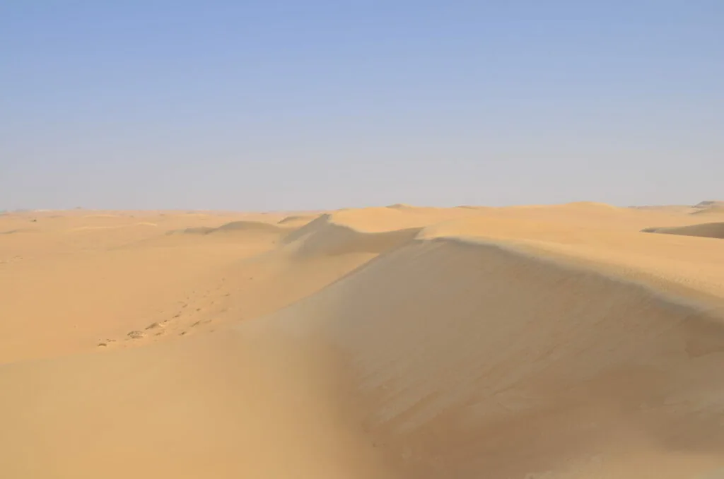 Rolling sand dunes in a desert landscape under clear blue sky