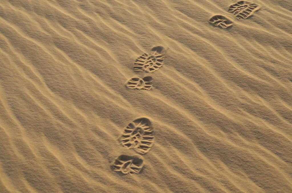 Footprints and boot impressions in rippled sand dunes