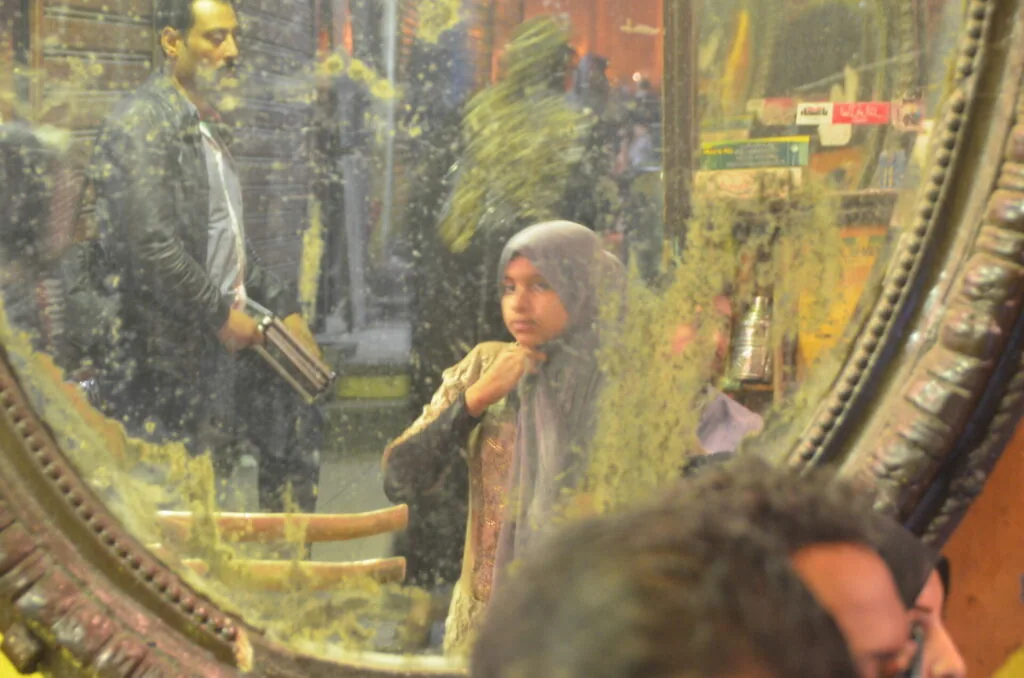 Diorama scene viewed through ornate frame showing figure in period clothing with man in suit in background