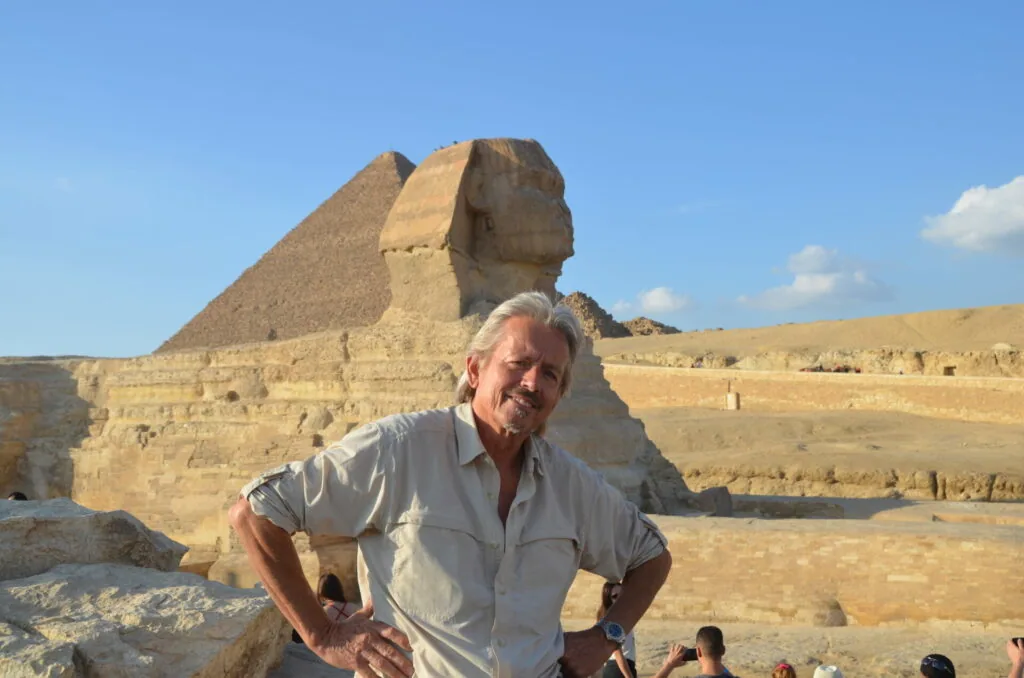 Man in light-colored shirt posing in front of the Great Sphinx with pyramid in background