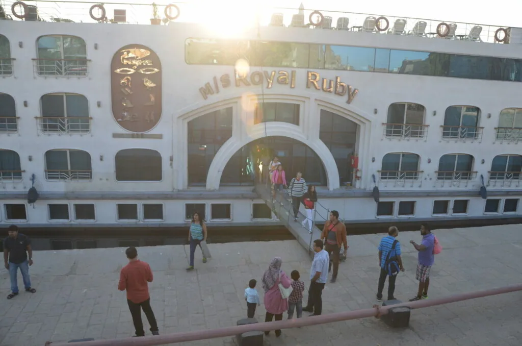 White cruise ship named Nile Royal Ruby docked at waterfront with passengers boarding via gangway