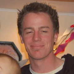 Man with short brown hair wearing white shirt indoors