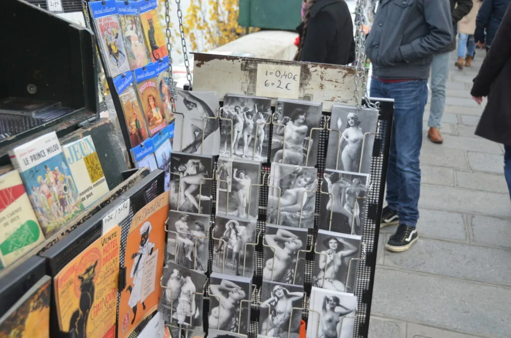 Vintage black and white photographs displayed on rack at outdoor market stall with colorful posters
