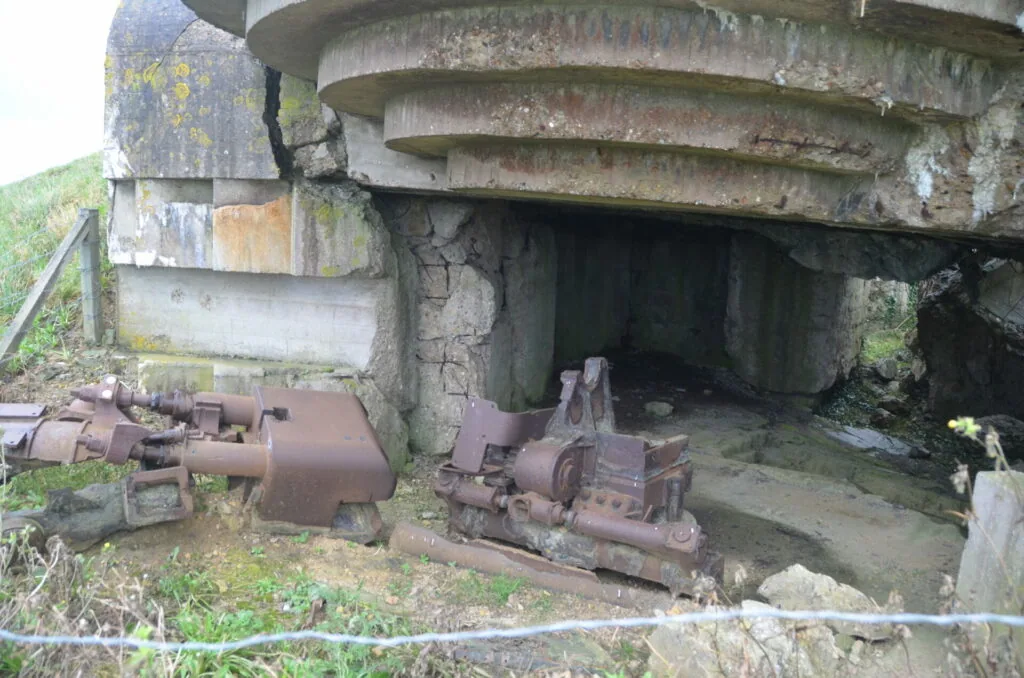 Abandoned concrete fortification with rusted industrial machinery and gears visible inside the entrance structure