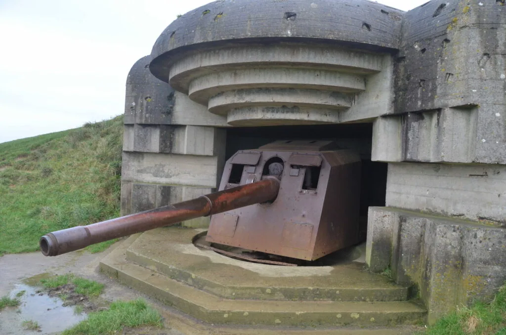 Concrete bunker with domed roof and protruding rusted metal gun barrel from turret