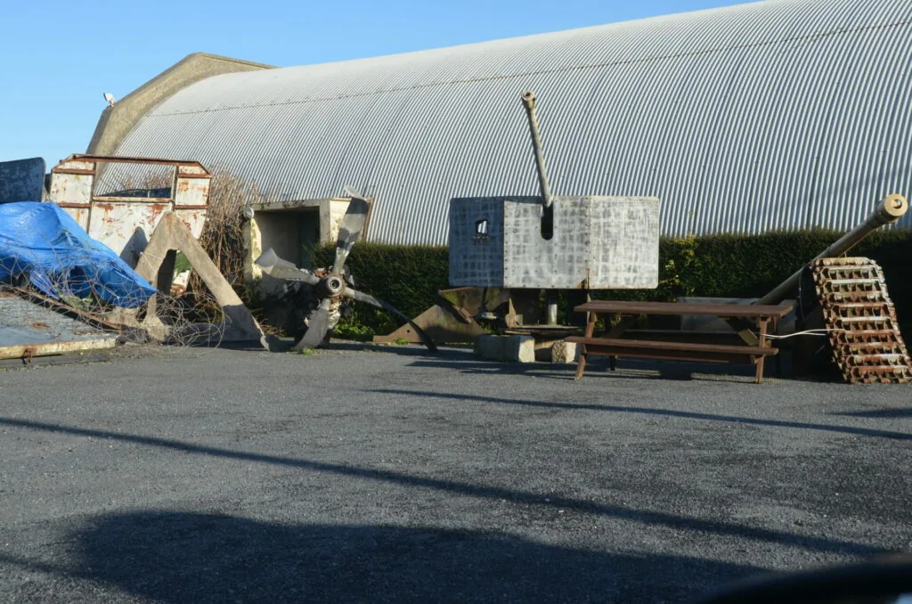 Weathered industrial farm equipment and metal structures beside a corrugated metal barn building