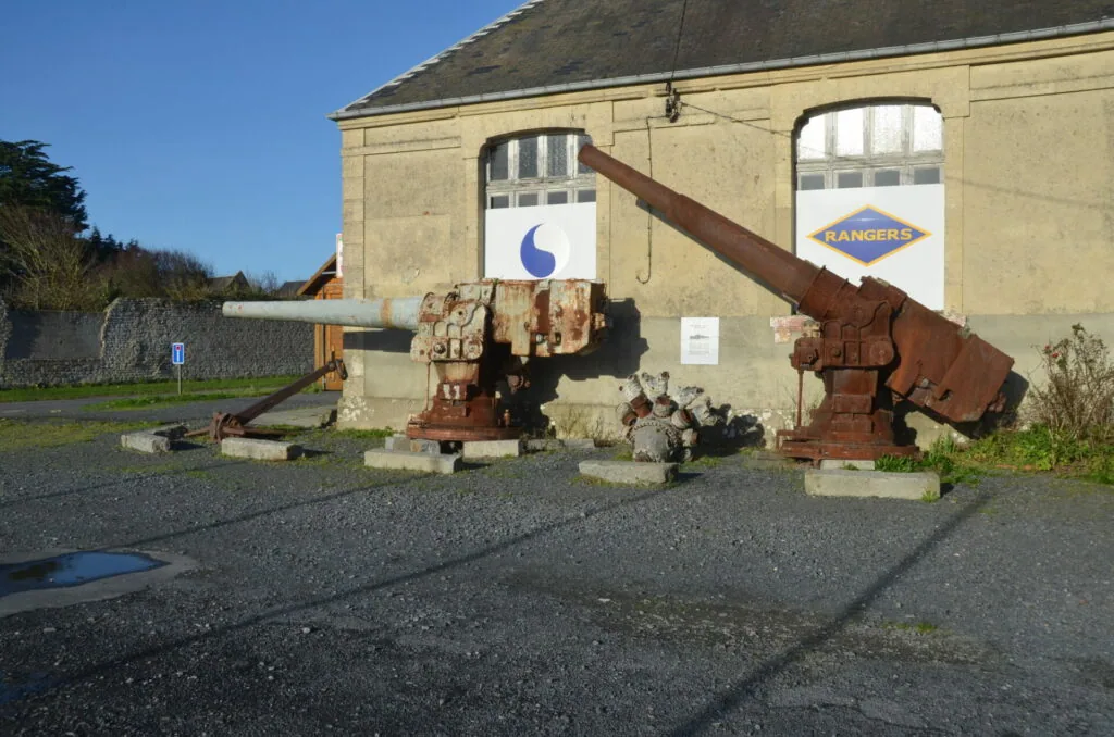 Rusted industrial machinery displayed outside a cream-colored building with blue logo signage