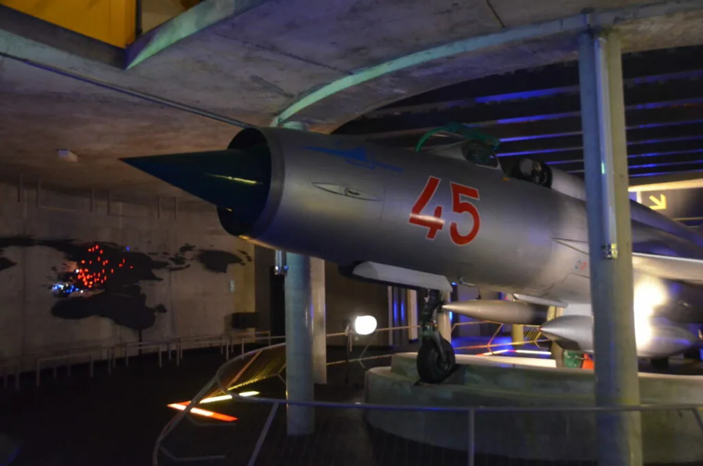 Military jet aircraft with red number 45 on fuselage displayed indoors under blue lighting in a museum setting
