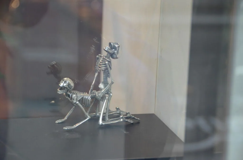 Silver skeletal figures displayed behind glass in a museum case