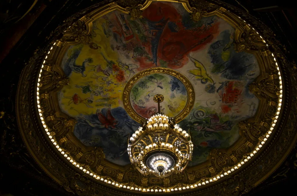 Ornate ceiling dome with painted frescoes and decorative crystal chandelier in gold frame