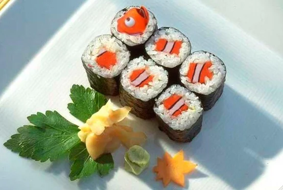 Six pieces of sushi rolls with red filling arranged on a white plate, garnished with green parsley and decorative orange star-shaped elements