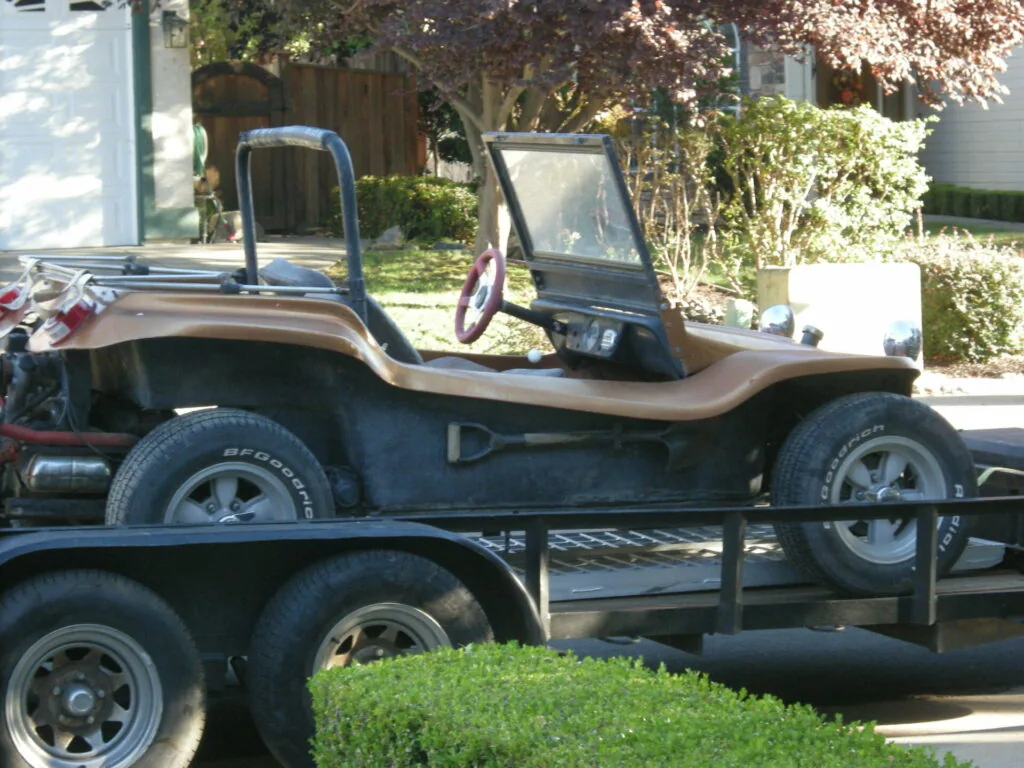 Custom jeep with brown and black two-tone paint parked on a flatbed trailer in a residential driveway