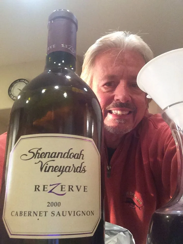 Man with white hair smiling next to bottle of Shenandoah Vineyards Reserve Cabernet Sauvignon 2000