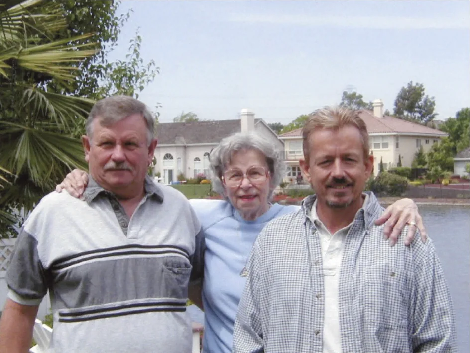 Three adults posing together outdoors with waterfront homes and palm trees in background