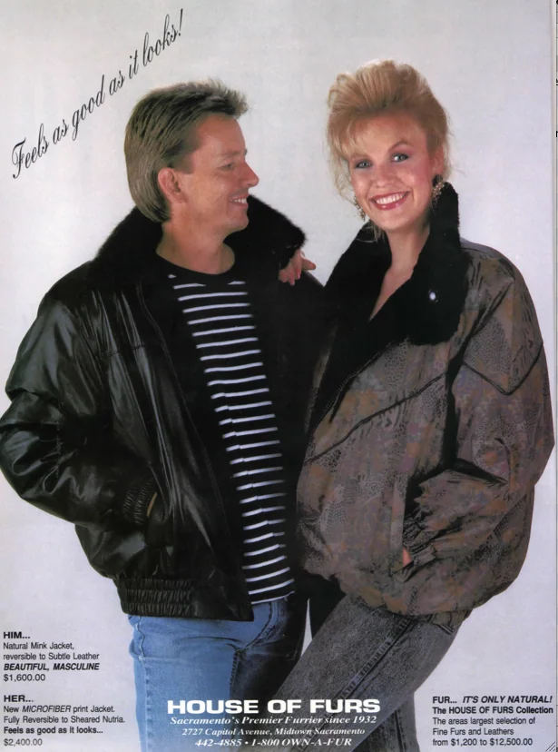 Man and woman wearing black fur-lined jackets smiling at each other