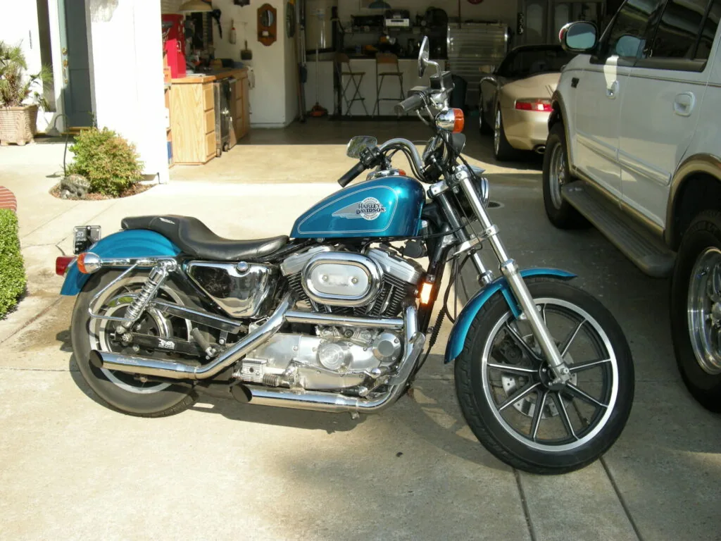 Blue and chrome motorcycle parked in a garage driveway next to a silver vehicle