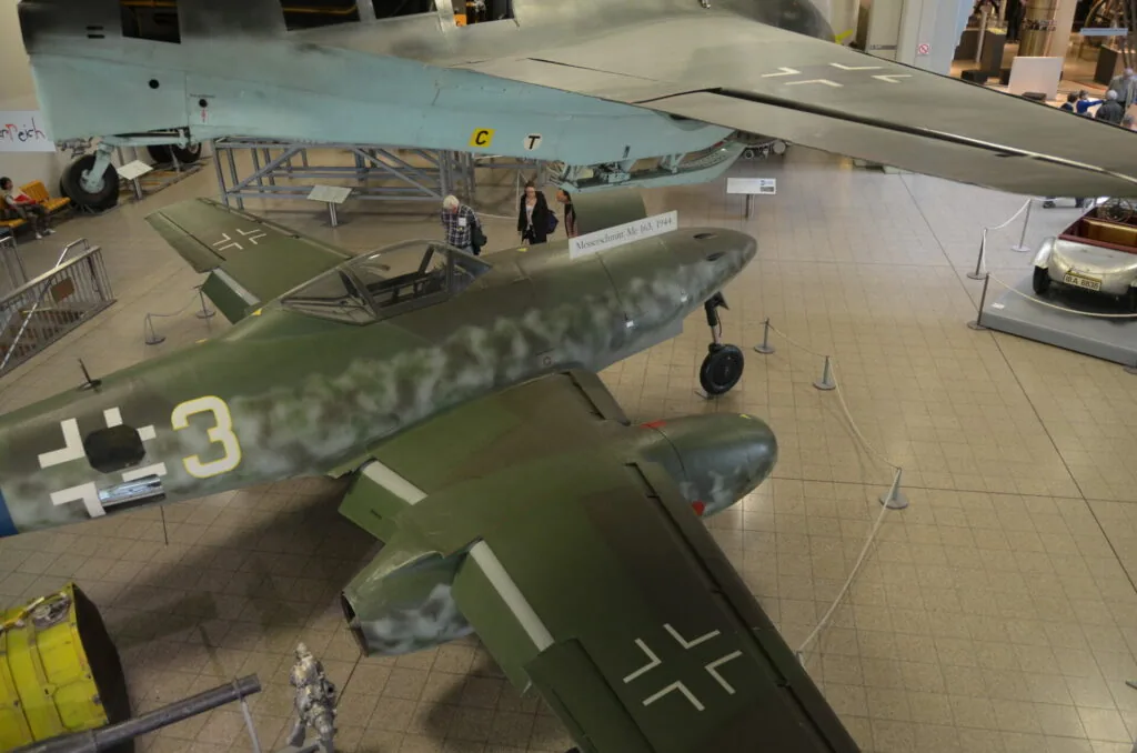 Military aircraft on display in museum hangar with identification markings on fuselage and wings