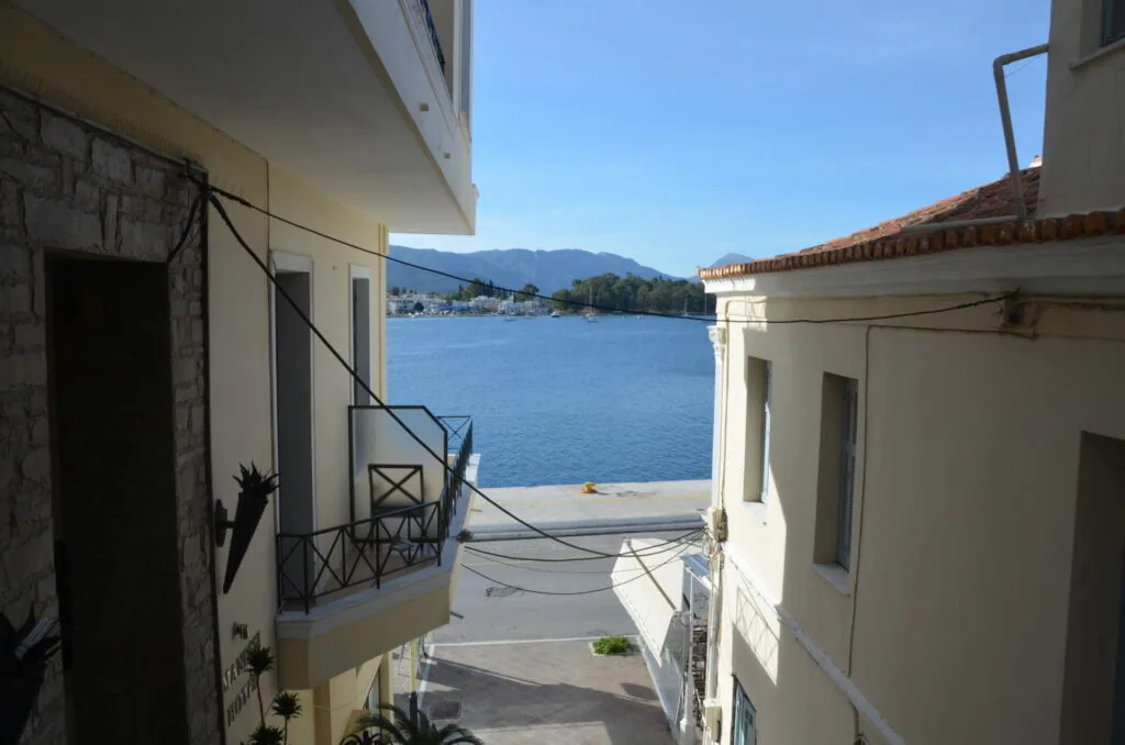 Waterfront buildings with view of blue bay, mountains, and boats in distance