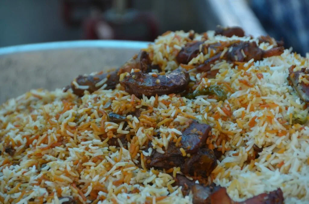 Biryani rice dish with meat pieces in a white bowl