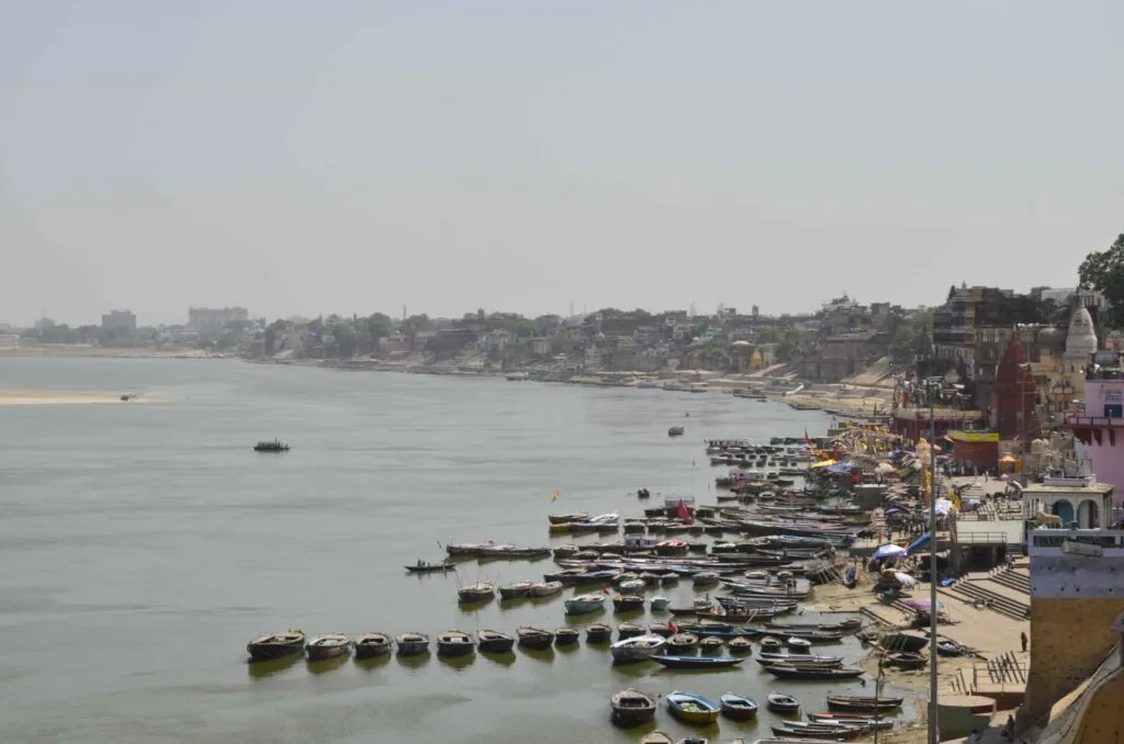 Riverfront city view with numerous small boats moored along the shore and buildings lining the waterside