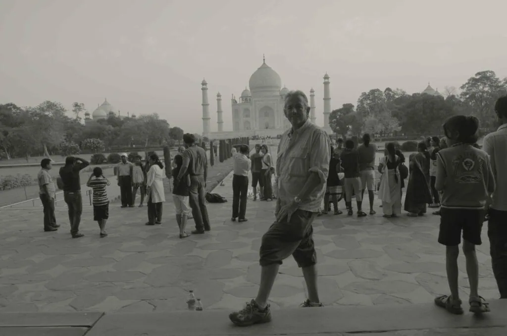 Black and white photograph of tourists on a plaza in front of a domed monument with minarets across a waterway