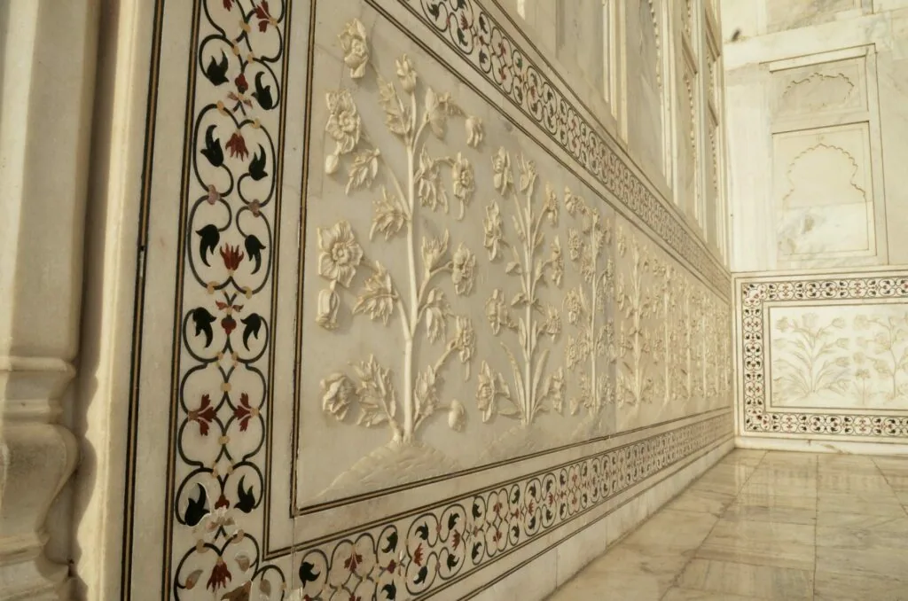 Ornate marble wall with inlaid floral patterns and decorative borders in relief