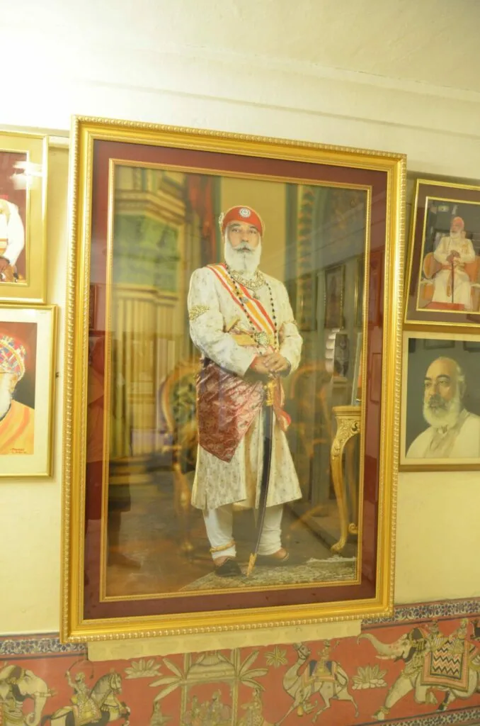 Framed portrait painting of a bearded man wearing traditional Russian clothing including an embroidered white shirt, patterned vest, and red cap, displayed in a gold-framed museum setting