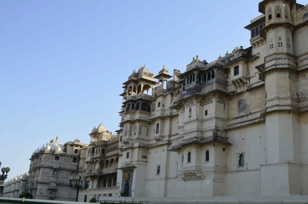 Multi-story ornate palace with cream-colored stone walls, domed towers, and intricate architectural details under clear blue sky