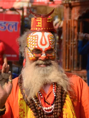 Man with long white beard wearing ornate red and gold religious attire and forehead marking