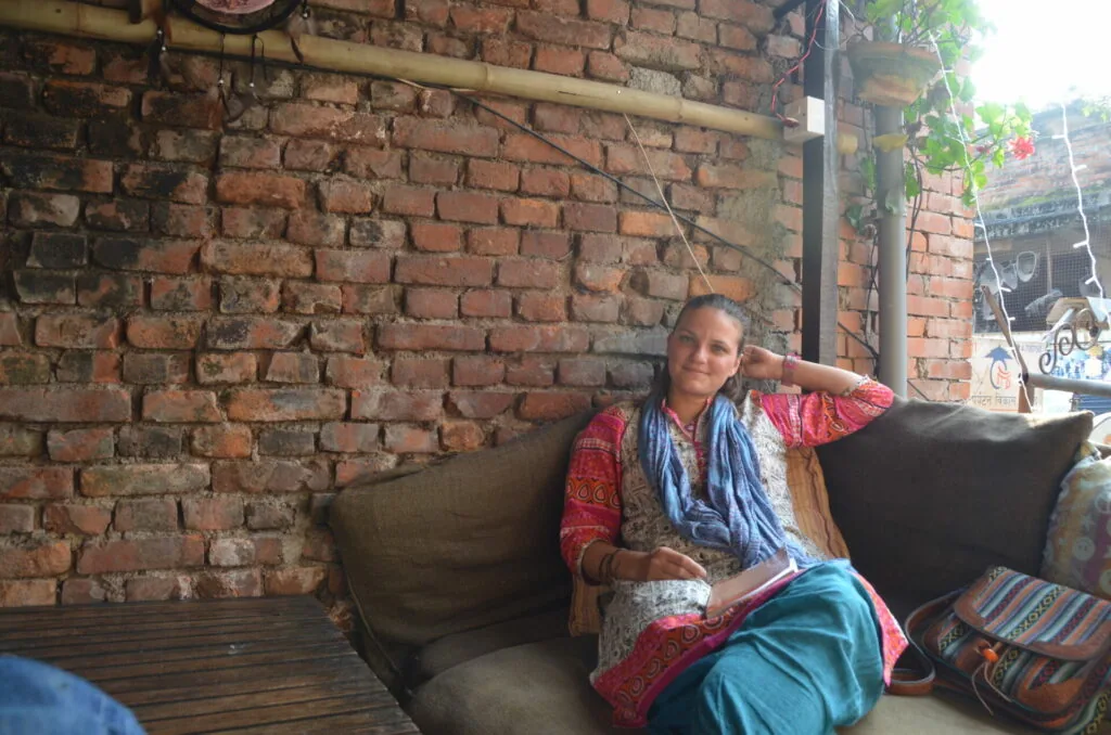 Woman in colorful traditional clothing sitting on dark couch against exposed brick wall