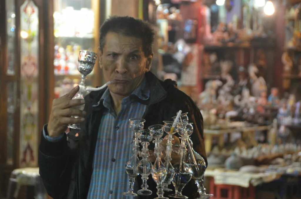 Man holding glass trophy in front of shop display with decorative figurines