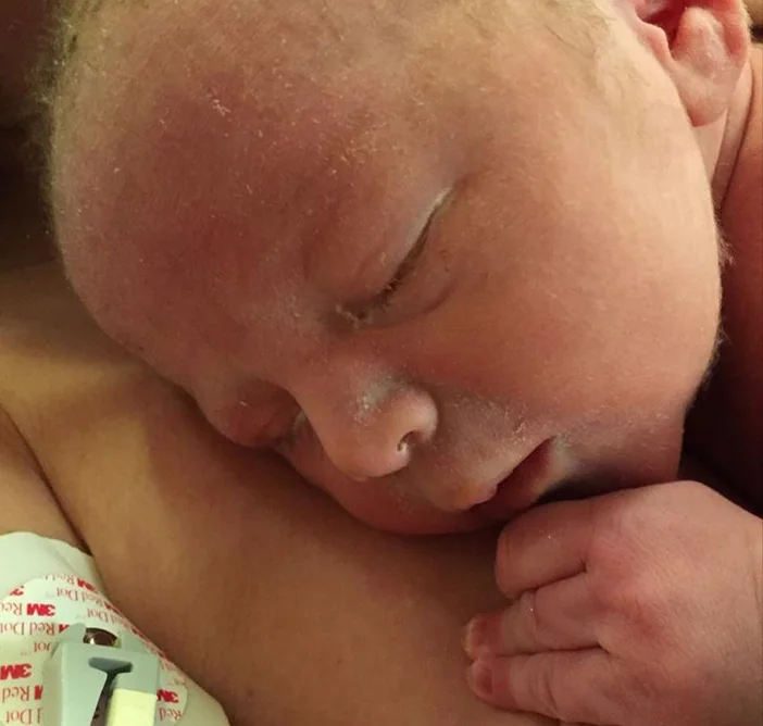 Sleeping newborn baby with peaceful expression resting on parent's shoulder