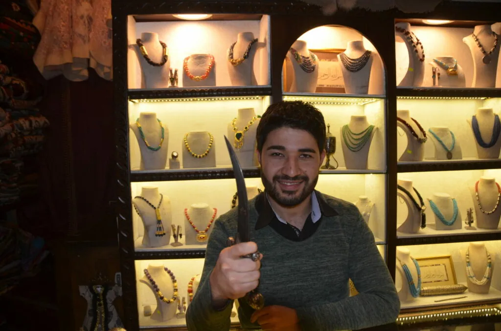 Man holding a baseball bat posing in front of illuminated jewelry display cases