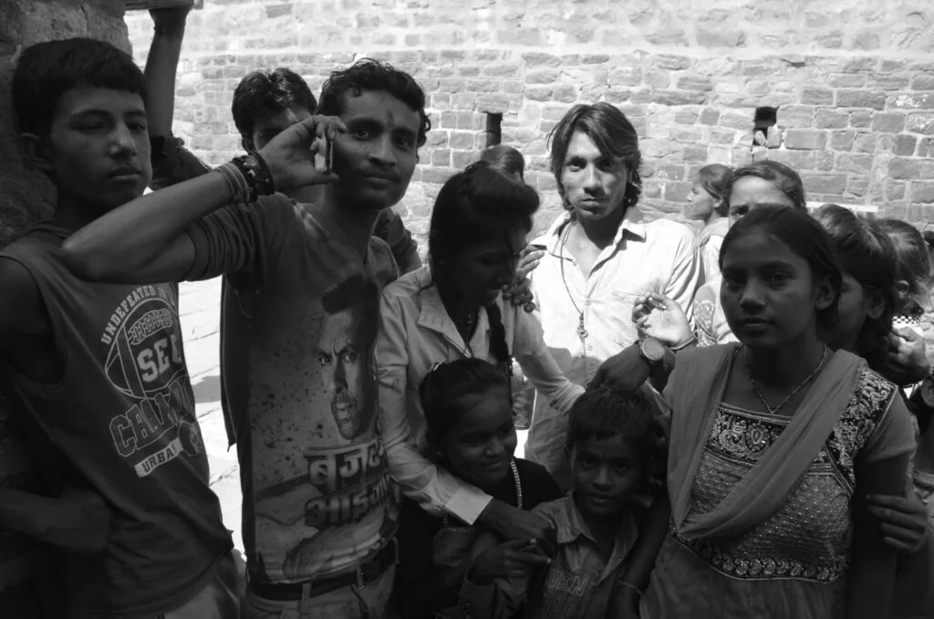 Group of teenagers and young adults standing together against a brick wall in black and white