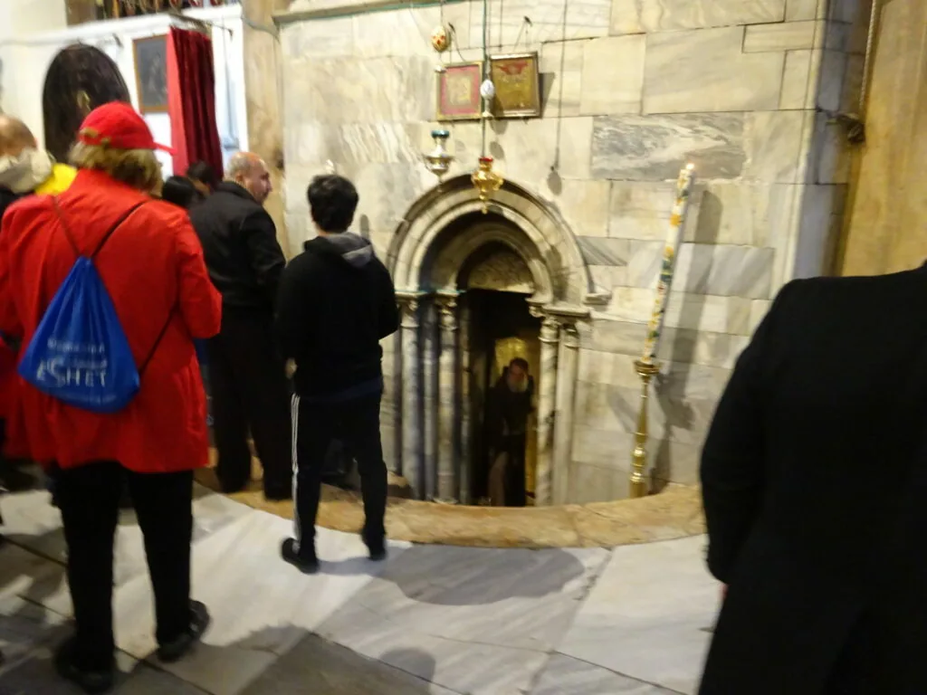 Visitors viewing a stone archway with religious iconography and hanging ornaments in a church interior