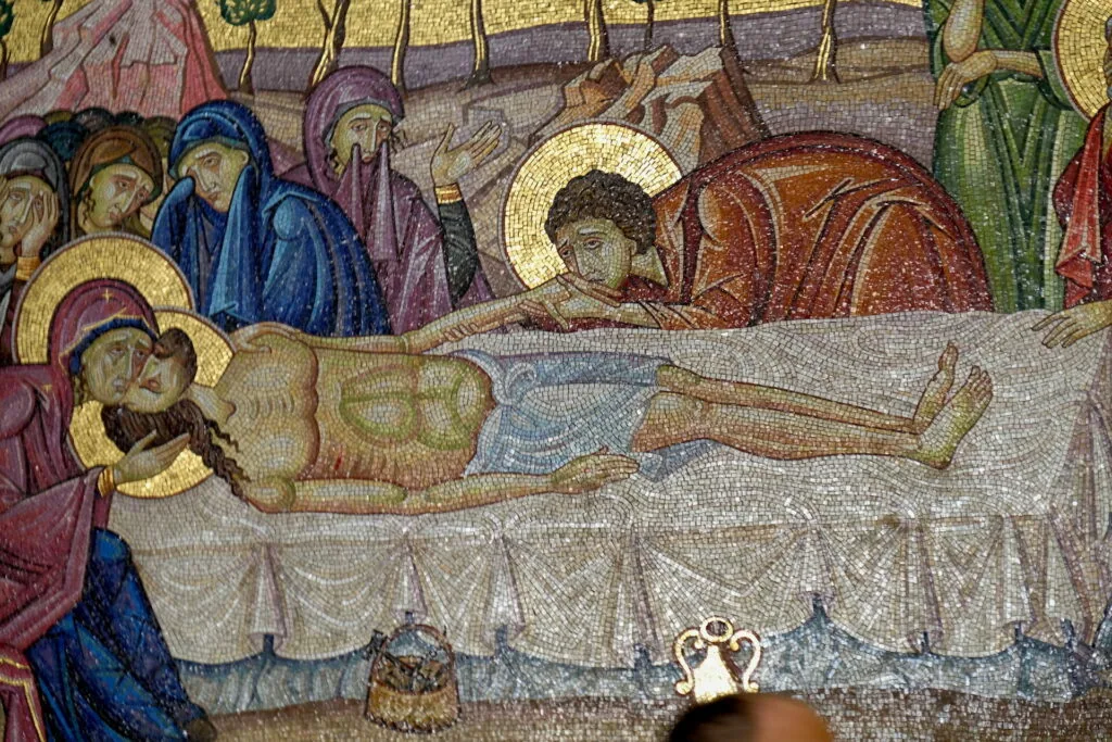 Byzantine mosaic depicting a saint with halo lying in repose, surrounded by robed figures with halos and gold backgrounds