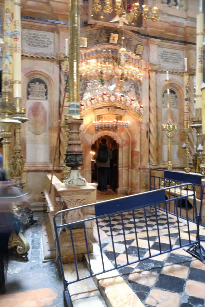 Interior of ornate religious shrine with arched doorways, golden decorative elements, and barrier railing