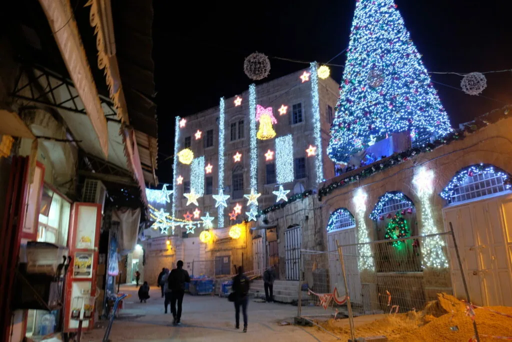 Night street scene with illuminated Christmas tree and decorated building with blue and white lights