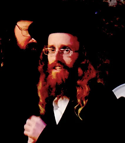 Man with long red beard and glasses wearing formal attire against dark background