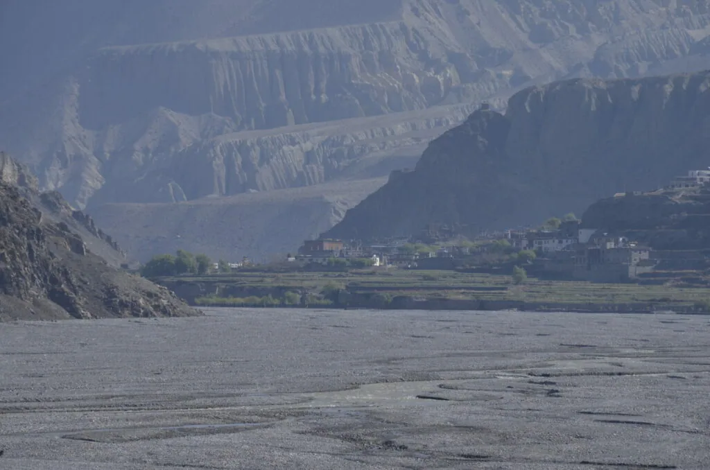 River valley with terraced mountains, settlement with green fields nestled between steep rocky cliffs