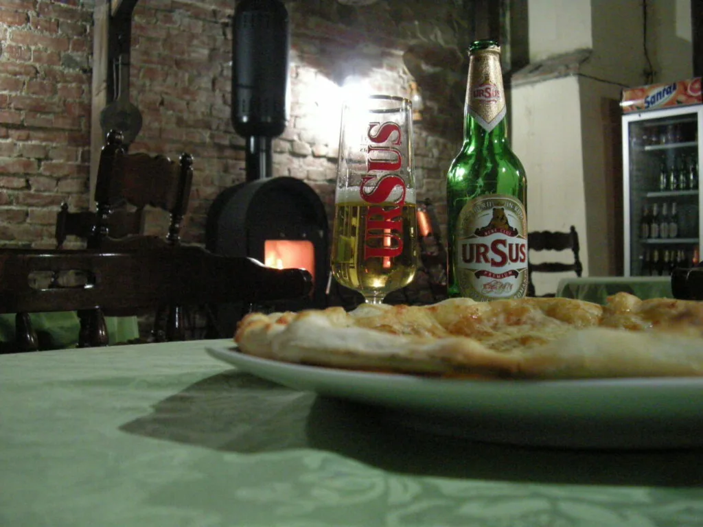 Pizza on a plate with beer bottles on a table in a rustic brick interior with a fireplace