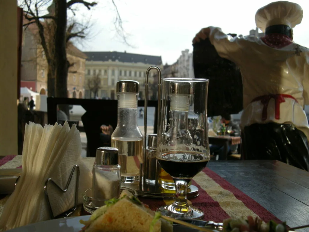 Outdoor café table with water glasses, napkins, and condiments overlooking a European square with historic buildings