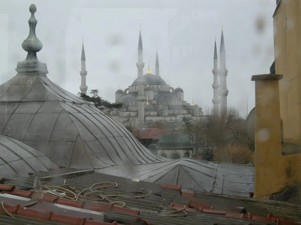 Historic mosque with multiple minarets visible across rooftops in overcast weather