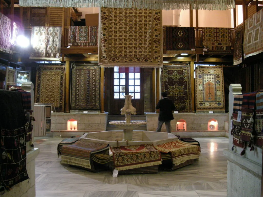 Interior of traditional Turkish carpet showroom with patterned textiles displayed on walls and central fountain