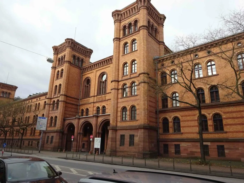 Red brick Victorian castle-style building with twin towers and arched windows on overcast day