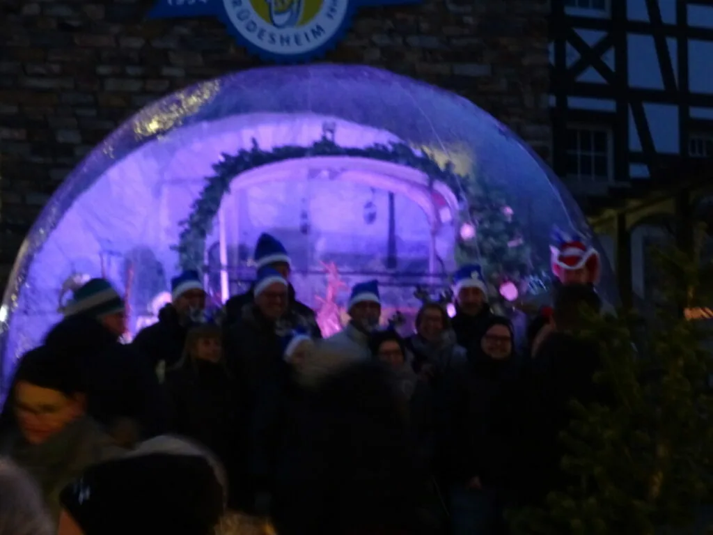 Crowd of people gathered under a large illuminated purple dome structure at night in an urban setting
